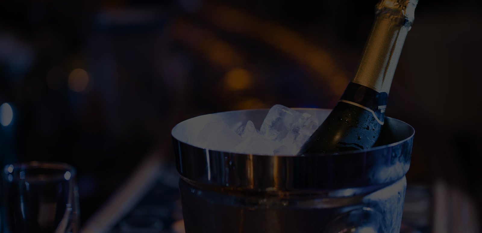 A champagne bottle in an ice bucket against softly lit bar surroundings.