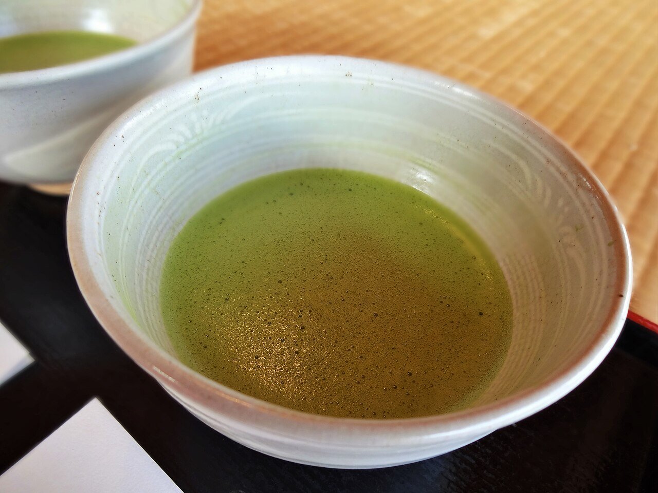 A ceramic bowl of green matcha tea on a tray at Hama-rikyū Garden in Tokyo.