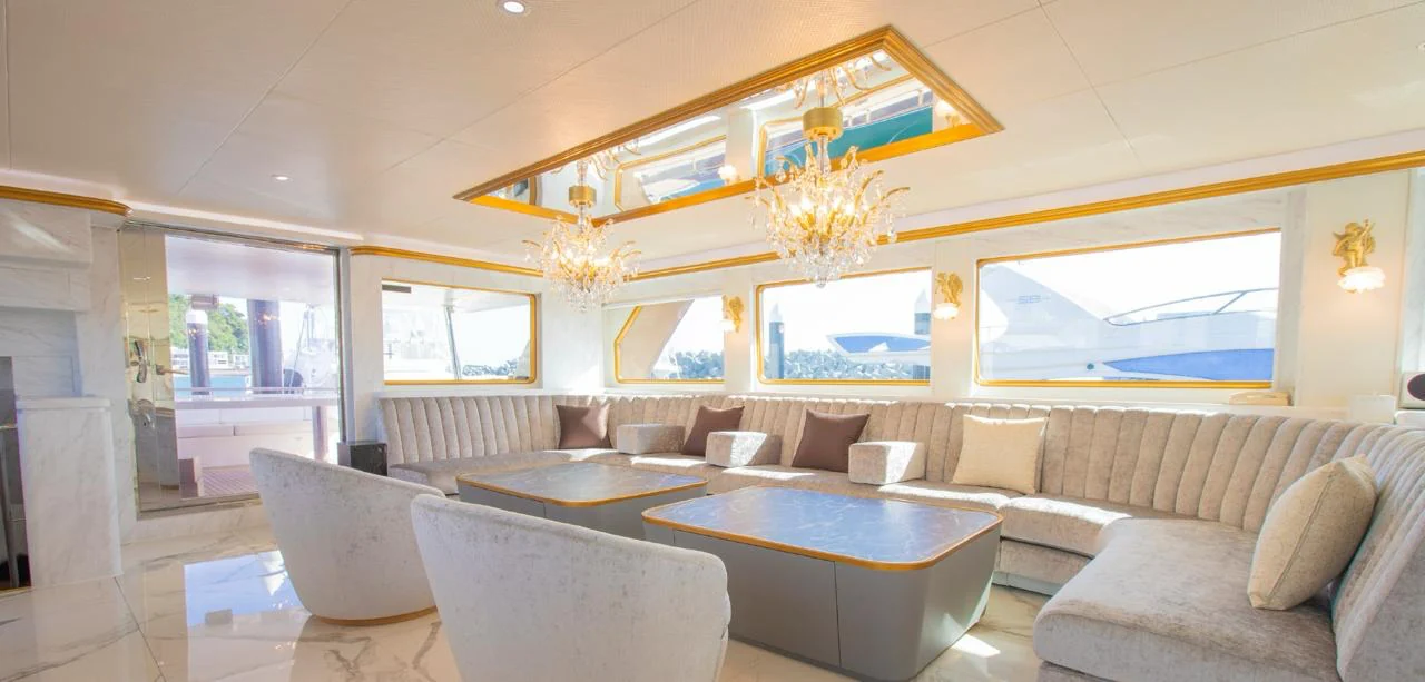 Bright yacht lounge with cream seating, gold trim and chandeliers.
