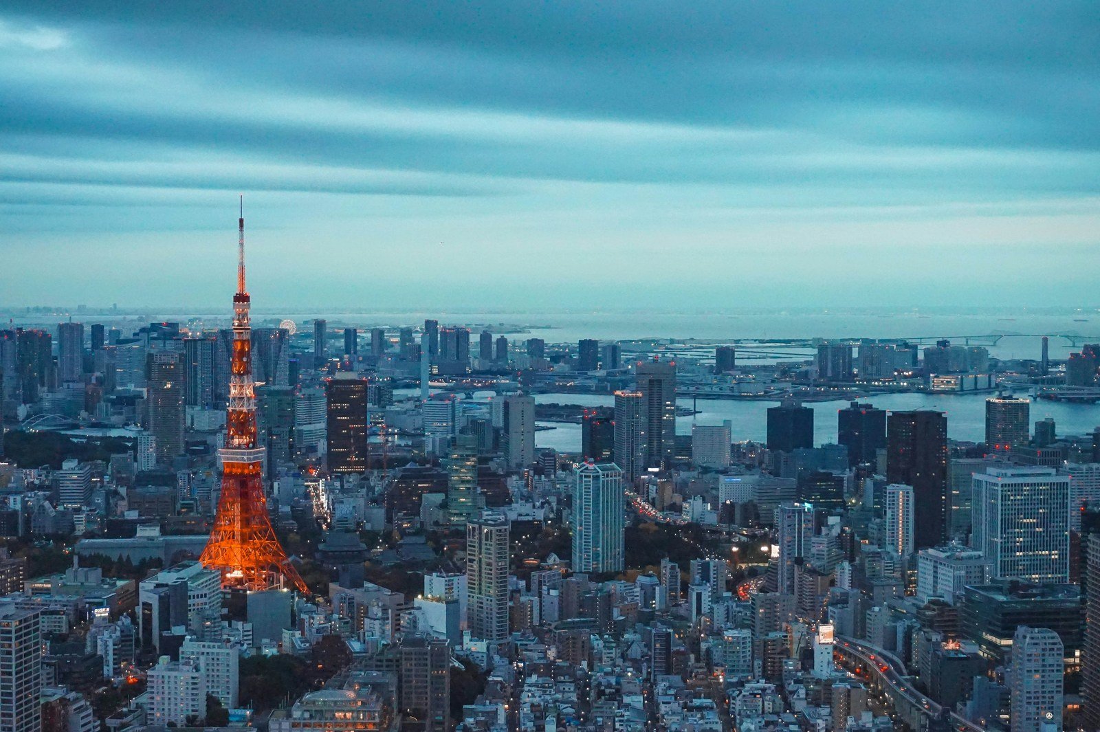 Tokyo Tower glowing above Tokyo’s city skyline and waterfront at dusk